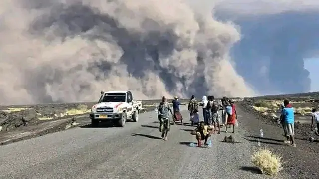 Foto yang dirilis oleh Biro Komunikasi Pemerintah Afar ini menunjukkan warga menyaksikan abu yang membubung dari letusan Gunung Berapi Hayli Gubbi yang telah lama tidak aktif di wilayah Afar, Ethiopia, pada Minggu (23/11/2025).