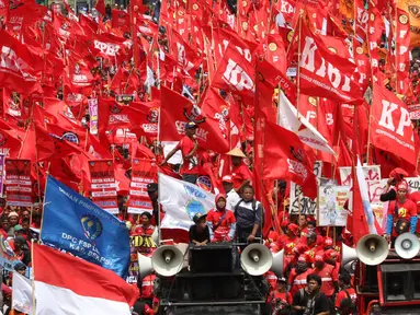 Sejumlah buruh membawa bendera berwarna merah saat aksi May Day 2016 di Jakarta, Minggu (1/5). Kaum buruh mengajukan tuntutan menolak upah murah serta pencabutan PP No. 78 Tahun 2015. (Liputan6.com/Angga Yuniar)