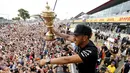 Pembalap Formula 1, Lewis Hamilton menunjukan trofi  ke pengemarnya usai berlaga di Grand Prix Formula 1 Silverstone di Inggris, (5/7/2015). Hamilton berhasil finish di urutan pertama dengan waktu 1 jam 31 menit 27,729 detik. (Reuters/Hoch Zwei)