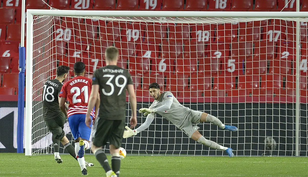 Gelandang Manchester United, Bruno Fernandes (kiri) mencetak gol kedua timnya melalui eksekusi penalti ke gawang Granada dalam laga leg pertama perempatfinal Liga Europa 2020/2021 di Nuevo Los Carmenes Stadium, Granada, Kamis (8/4/2021). Manchester United menang 2-0. (AFP/Cristina Quicler)
