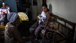 Fe Maria LLouvet mengipasi putrinya Disley Martinez saat dia menyusui putranya yang baru lahir, selama pemadaman listrik pagi di Regla, Kuba, Senin, 1 Agustus 2022. Pemadaman tersebut kemungkinan akan menyebabkan gangguan jangka pendek pada operasi bisnis, utilitas, telekomunikasi, dan mungkin transportasi. (AP Photo/Ramon Espinosa)