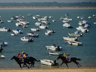 Peserta memacu kudanya saat mengikuti lomba pacuan kuda pantai tahunan di Sanlucar de Barrameda, dekat Cadiz, Spanyol (17/8). Pacuan kuda ini bermula dari para nelayan yang berlomba mengangkut tangkapan mereka melalui pantai. (AFP Photo/Cristina Quicler)