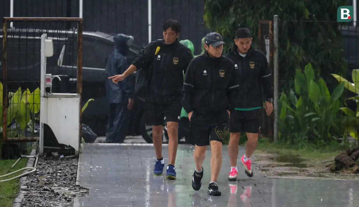 Pelatih kepala Timnas Indonesia, Shin Tae-yong (tengah) berjalan menembus hujan saat latihan Timnas Indonesia menjelang laga leg pertama semifinal Piala AFF 2022 menghadapi Vietnam yang berlangsung di Lapangan A, Kompleks Gelora Bung Karno, Jakarta, Rabu (04/01/2023). (Bola.com/Bagaskara Lazuardi)