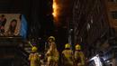 Petugas pemadam kebakaran memadamkan api di lokasi konstruksi di Hong Kong, Jumat (3/3/2023). Dinas Kebakaran pun bergerak cepat untuk melakukan pemadaman. (AP Photo/Louise Delmotte)