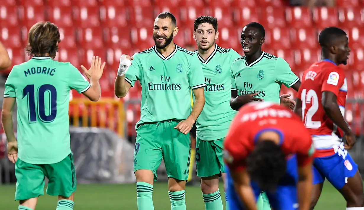 Penyerang Real Madrid, Karim Benzema (kedua kiri) berselebrasi usai mencetak gol ke gawang Granada pada pertandingan lanjutan La Liga Spanyol  di stadion Nuevo Los Carmenes di Granada (13/7/2020). Madrid menang tipis 2-1 atas Granada. (AFP/Jorge Guerrero)