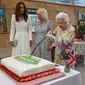 Ratu Inggris Elizabeth II mencoba memotong kue dengan pedang, yang dipinjamkan kepadanya oleh The Lord-Letnant of Cornwall, Edward Bolitho, untuk merayakan inisiatif 'The Big Lunch' di The Eden Project, dekat St Austell di barat daya Inggris pada 11 Juni 2021. (OLI SCARFF / POOL / AFP)