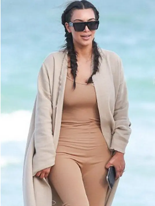 Berbeda dengan Kourtney, Kim justru terlihat formal, ia mengenakan jumpsuit berwarna cokelat muda dan jcoat tebal panjang. Netizen pun menilai Kim sedang salah kostum. (viaceshowobiz/Bintang.com)