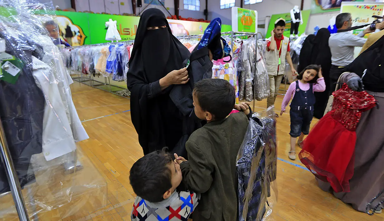 Anak-anak Yaman mengenakan pakaian baru selama pembagian pakaian amal di stadion di ibu kota Sanaa (25/4/2021). Pembagian pakaian amal bagian dari tindakan untuk membantu orang miskin selama bulan suci puasa Ramadhan. (AFP/Mohammed Huwais)