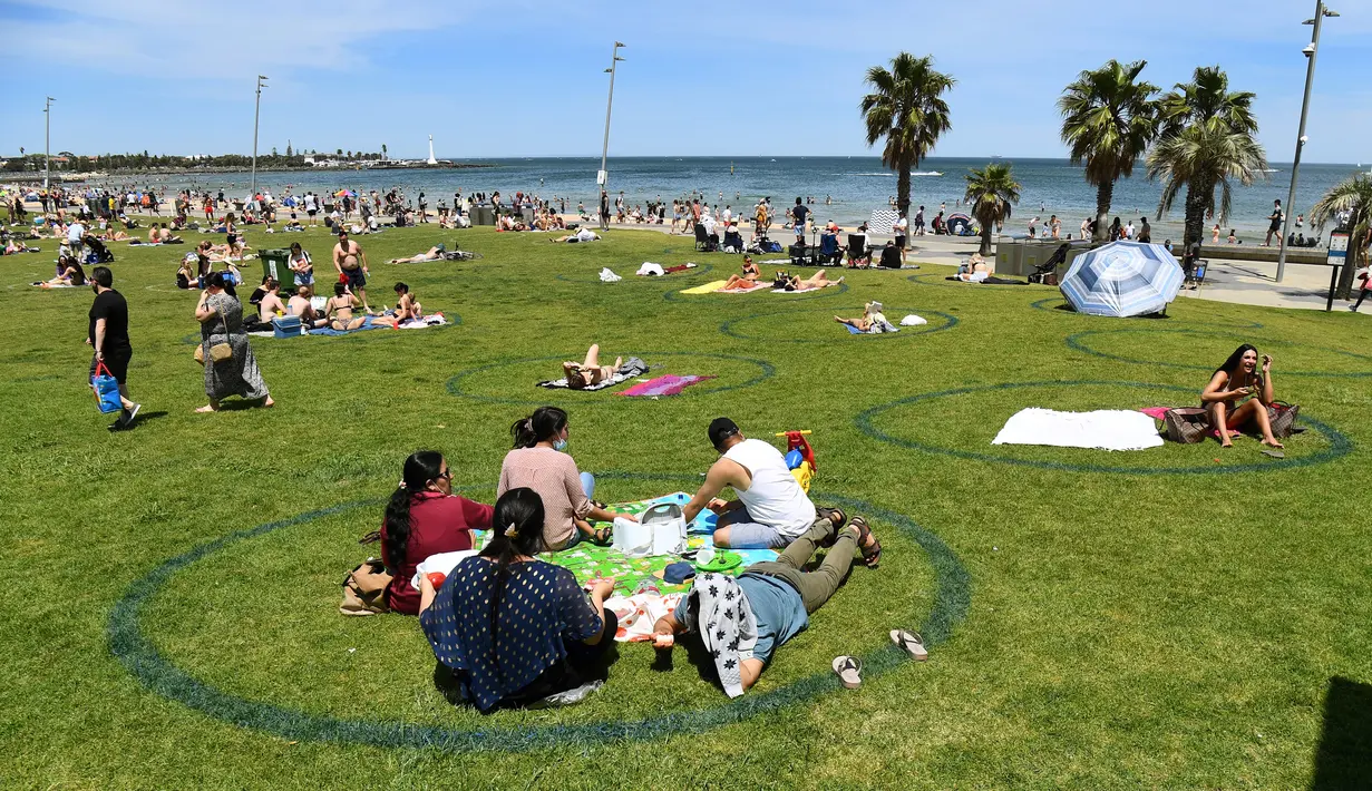 Wisatawan berjemur saat menikmati cuaca hangat di Pantai St Kilda Melbourne, Australia, Selasa (3/11/2020). Negara bagian Victoria di Australia mencatat nol kasus penularan COVID-19 selama empat hari berturut-turut setelah berjuang melawan gelombang kedua wabah pandemi. (AFP/William West)