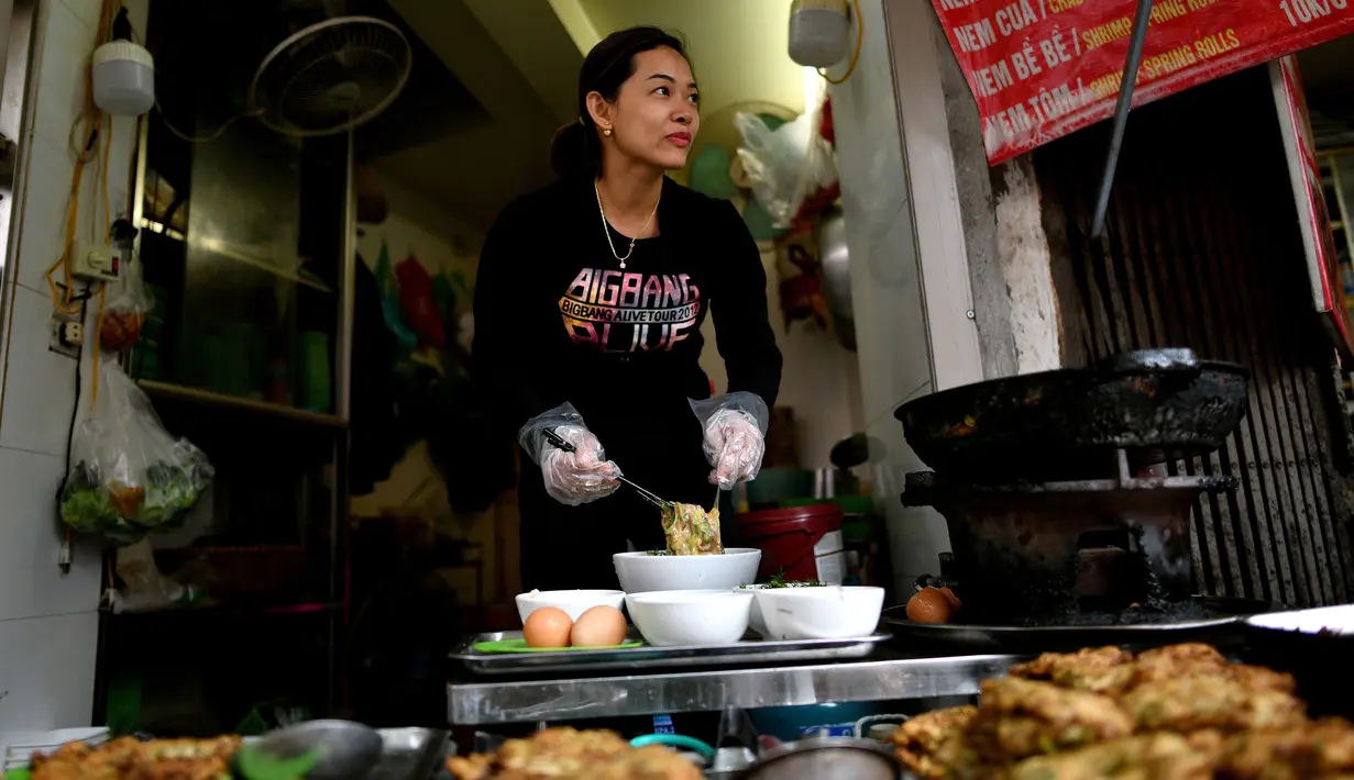 Penjual membuat kuliner cha ruoi di sebuah kios di Hanoi, Vietnam, Jumat (14/12). Para penjual cha ruoi biasanya menyemangati para pembeli agar tidak takut dengan isian cacing yang tampak menjijikan. (Manan Vatsyayana/AFP)