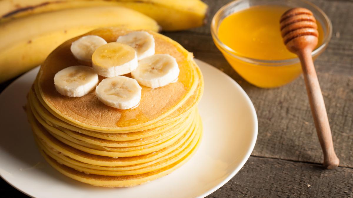Tumpukan pancake madu lembut yang disajikan dengan siraman madu dan buah segar, sempurna untuk sarapan atau camilan