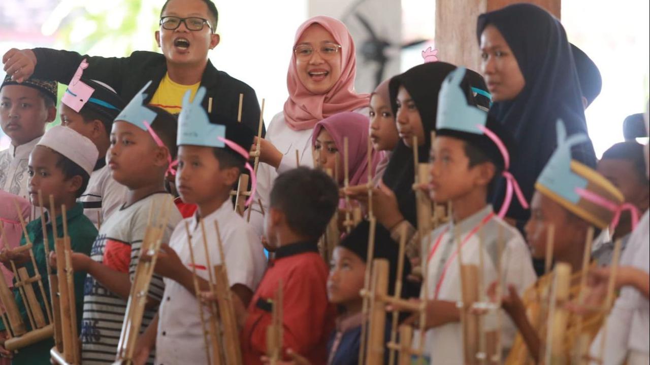 Tak dinyana, di tengah kepolosan anak-anak memainkan alat musik bambu yang digoyang-goyang itu, Bupati Ipuk tertarik untuk turut memainkannya. Tak ayal aplause meriah mengiringi permainan tersebut.