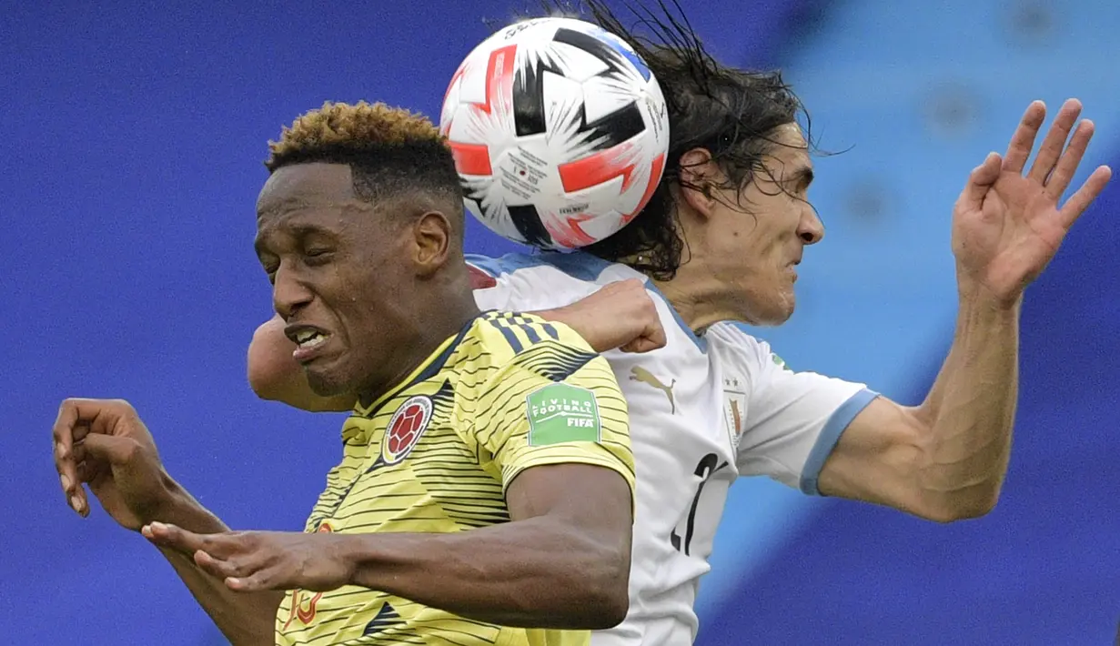 Bek Kolombia, Duvan Zapata dan penyerang Uruguay, Edinson Cavani melompat saat berebut bola dalam laga Kualifikasi Piala Dunia 2022 zona Amerika Selatan di stadion Metropolitano, Barranquilla, Jumat (13/11/2020). Uruguay mengalahkan  Kolombia 3-0. (Raul ARBOLEDA / AFP)