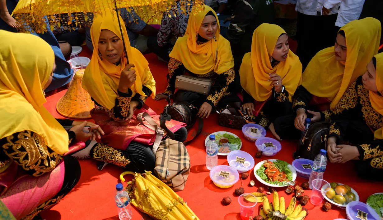 Sejumlah wanita menunggu untuk menikmati makan siang selama perayaan maulid akbar Nabi Muhammad SAW di Banda Aceh, Aceh, Kamis (6/2/2020). Acara itu menyediakan 808 hidangan dari 90 desa dan instansi pemerintah dengan mengundang 25.000 tamu dari berbagai daerah. (Photo by Chaideer MAHYUDDIN / AFP)