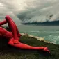 Awan Gelombang 'Tsunami' Muncul di Langit Sydney. Sebuah Patung yang sedang dipamerkan di Pantai Bondi dengan latar belakang awan Tsunami (Reuters)