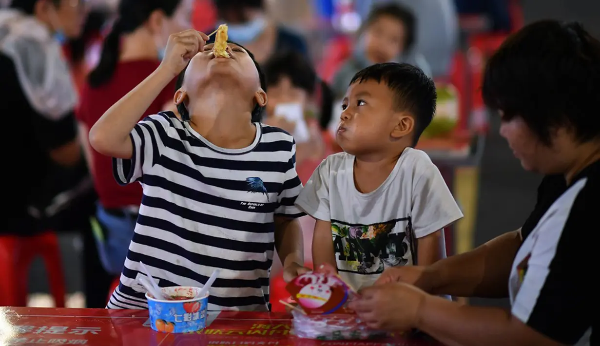 Anak-anak menikmati makanan ringan di sebuah pasar malam di Haikou, ibu kota Provinsi Hainan, China selatan (26/3/2020). Provinsi Kepulauan Hainan di China selatan pada Selasa (24/3) mencatatkan penurunan jumlah kasus penyakit coronavirus baru (COVID-19) yang ada menjadi nol. (Xinhua/Guo Cheng)