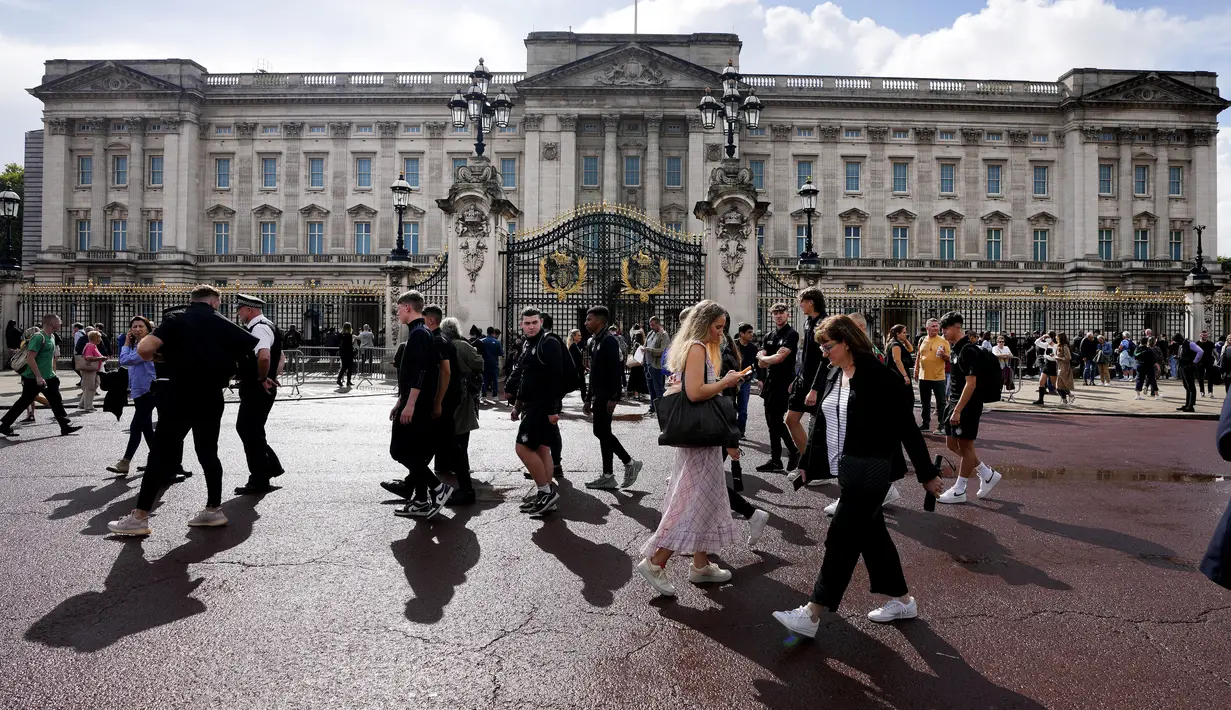 Turis berdiri di depan Istana Buckingham di London, Kamis (8/9/2022).  Istana Buckingham mengatakan Ratu Elizabeth II telah ditempatkan di bawah pengawasan medis karena dokter "memperhatikan kesehatan Yang Mulia." Anggota keluarga kerajaan pergi ke Skotlandia untuk bersama raja berusia 96 tahun itu. (AP Photo/Frank Augstein)