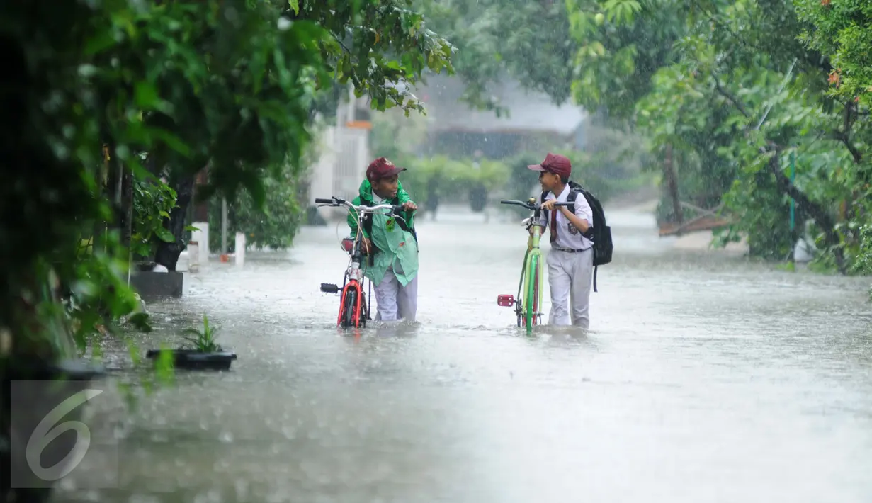 Dua anak sekolah membawa sepedanya melitasi banjir di perumahan Pondok Hijau Permai, Bekasi, Senin (20/2). Hujan berkepanjangan menyebabkan kali yang melintasi perumahan tersebut meluap. (Liputan6.com/Gempur M. Surya)