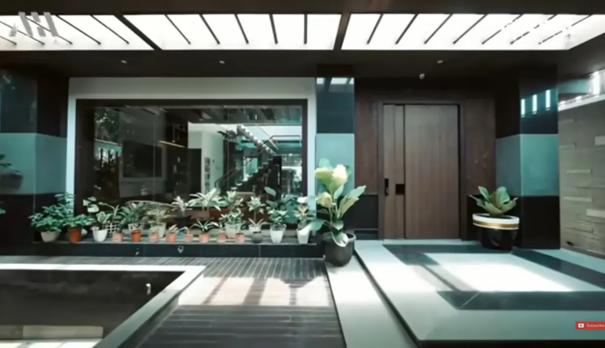 Kalau di seberang ruang tamu ada tempat gym yang juga luas. Rachel mengaku tak suka olahraga, tapi dibuat untuk motivasi olahraga. Kalau potret berikut untuk masuk ke ruang keluarganya. Banyak tanaman hingga terlihat asri. [Youtube/AH]