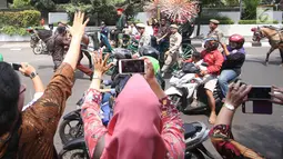 Gubernur DKI Jakarta Djarot Saiful Hidayat bersama istri Happy Farida menaiki delman sambil melambaikan tangan kepada warga dan pegawai Pemprov DKI Jakarta saat perpisahan dirinya di Balaikota DKI Jakarta, Minggu (15/10). (Liputan6.com/Immanuel Antonius)