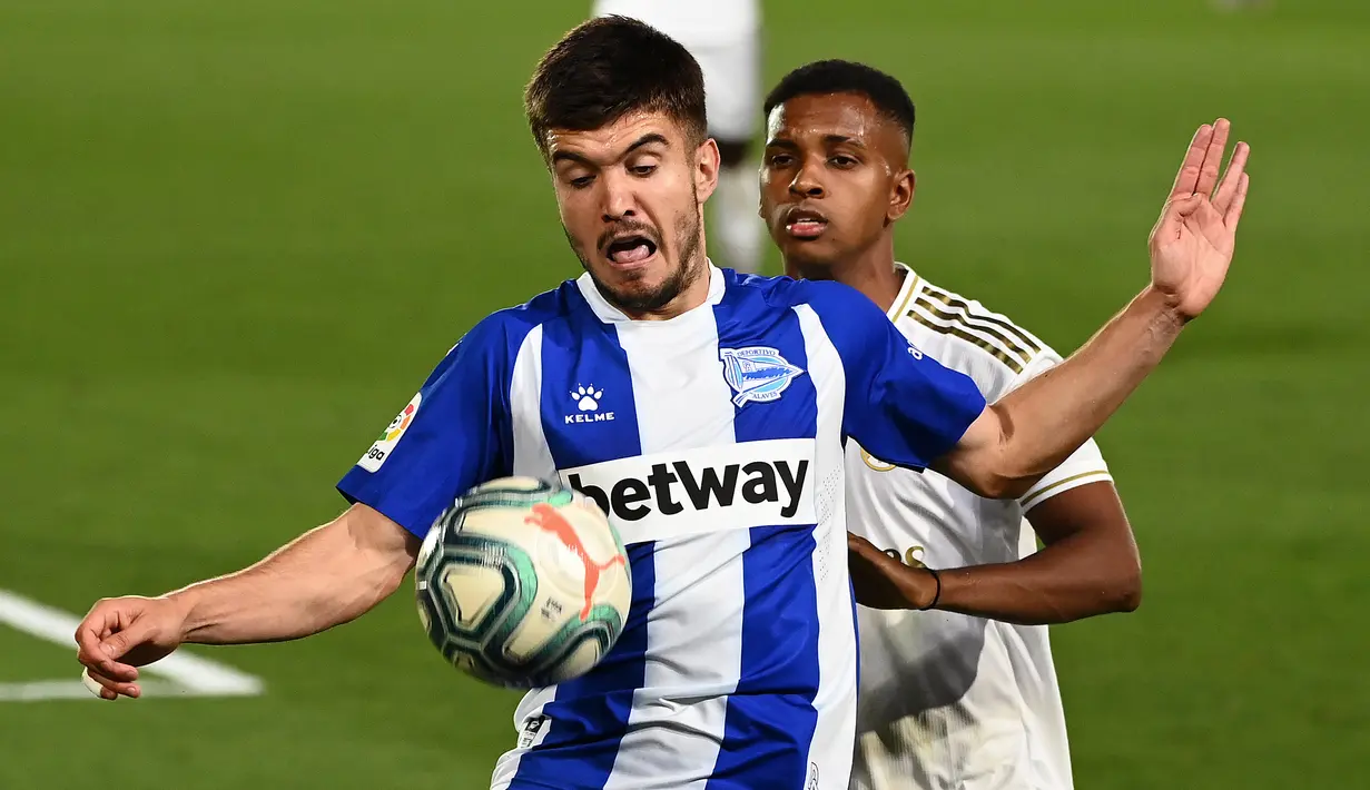 Bek Alaves, Martin Aguirregabiria berebut bola dengan penyerang Real Madrid, Rodrygo (kanan) pada lanjutan Liga Spanyol di stadion Alfredo di Stefano, Sabtu (11/7/2020). Real Madrid menang 2-0 lewat gol Karim Benzema dan Marco Asensio. (GABRIEL BOUYS/AFP)