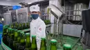 Seorang pekerja berdiri di depan lini produksi bir merek Taeha di Pabrik Bahan Makanan Unha Taesong, Pyongyang, Korea Utara, 6 April 2021. (KIM Won Jin/AFP)