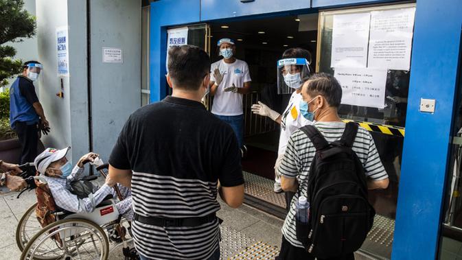 Petugas (tengah kanan) memberi isyarat kepada orang-orang yang menunggu dalam antrean di pusat pengujian virus corona COVID-19, Hong Kong, Selasa (1/9/2020). Hong Kong mulai melakukan tes massal virus corona COVID-19. (ISAAC LAWRENCE/AFP)