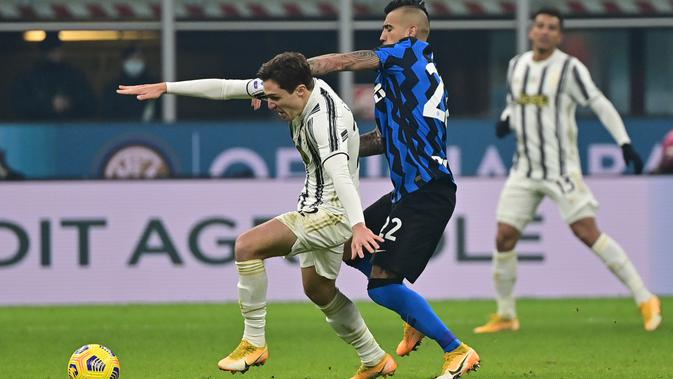 Gelandang Juventus, Federico Chiesa membaw bola dari kawalan gelandang Inter Milan, Arturo Vidal pada pertandingan lanjutan Liga Serie A Italia di stadion San Siro di Milan, Senin (18/1/2021). Inter menang atas Juventus 2-0. (AFP/Miguel Medina)