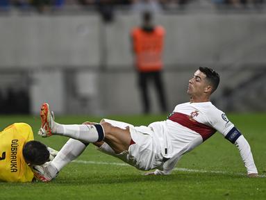 Pemain Portugal, Cristiano Ronaldo (kanan) berebut bola dengan kiper Slovakia, Martin Dubravka saat laga grup G Kualifikasi Euro 2024 di National Football Stadium in Bratislava, Slovakia, Sabtu (9/9/2023) dini hari WIB. Pertandingan tersebut diwarnai dengan insiden tekel horor Ronaldo ke kepala kiper Slovakia. (AP Photo/Radovan Stoklasa)