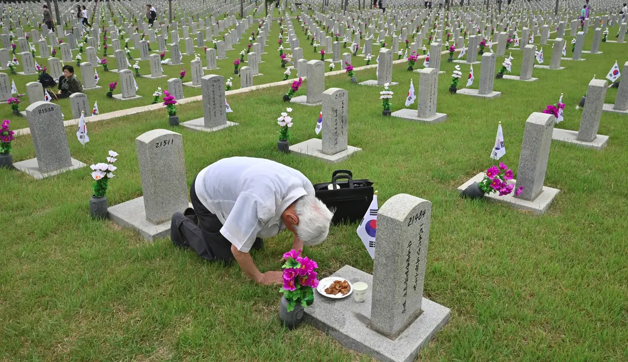 Seorang pria Korsel membungkuk memberi hormat di depan nisan kerabatnya yang gugur untuk negara pada Memorial Day di Pemakaman Nasional Seoul, Kamis (6/6/2019). Memorial Day didedikasikan untuk mengingat prajurit dan warga sipil yang gugur selama perang Korea antara 1950-1953. (Jung Yeon-je/AFP)