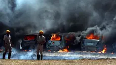 Petugas pemadam kebakaran berdiri dekat deretan mobil yang terbakar di area parkir pameran dirgantara Aero India 2019, Bangalore, India, Sabtu (23/2). Api melahap sekitar 300 mobil. (AP Photo/Parthi Bhan)