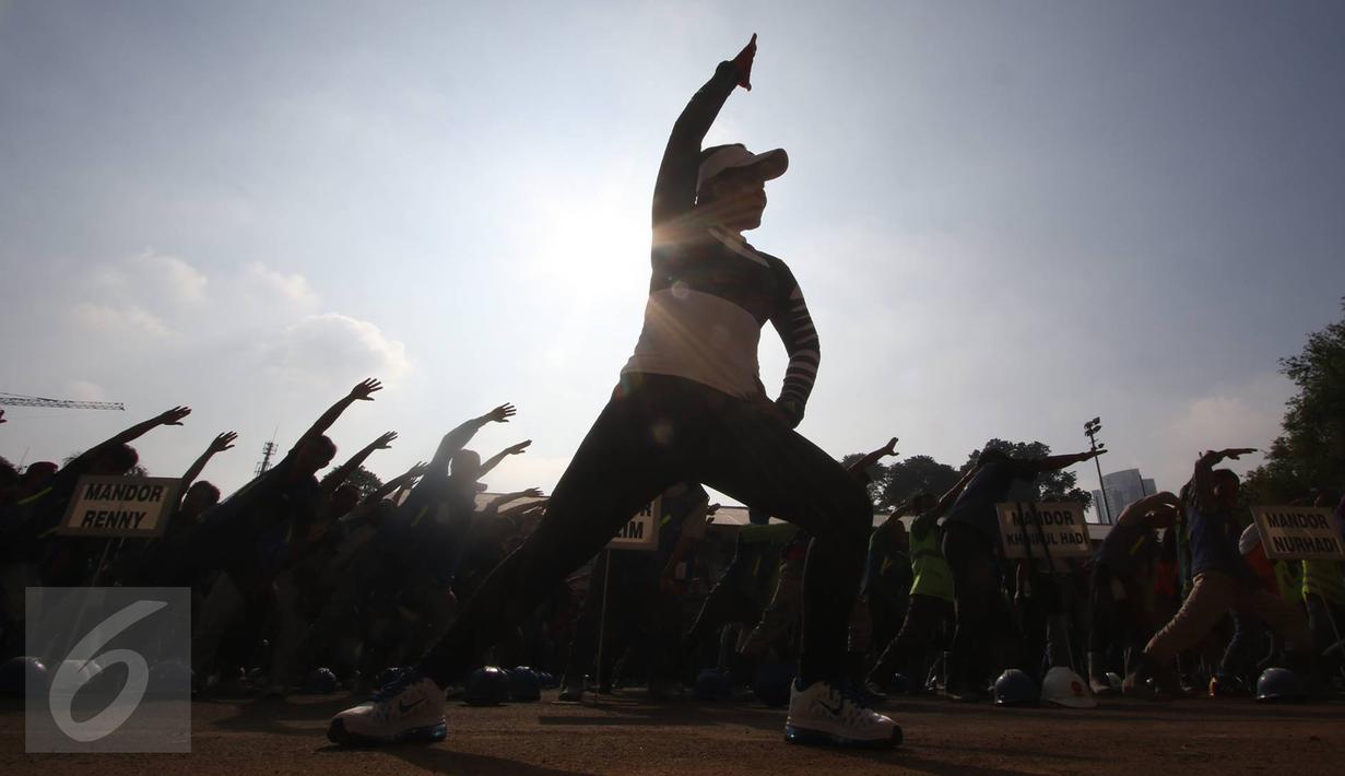 Pekerja renovasi Stadion Utama GBK mengikuti instruktur senam sebelum beraktivitas di kawasan Senayan, Jakarta, Jumat (17/3). Senam dilakukan untuk menjaga kebugaran pekerja yang rutin diadakan setiap Jumat pagi. (Liputan6.com/Immanuel Antonius)