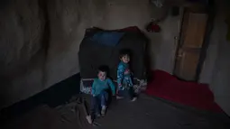 Dua orang anak duduk di dalam gua di kota Bamiyan, Kabul. Foto diambil pada 19 Juni 2015. Ratusan warga miskin Afghanistan terpaksa menghuni gua-gua tersebut untuk dijadikan rumah karena tak memiliki tempat tinggal. (AFP PHOTO / SHAH Marai)