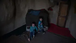Dua orang anak duduk di dalam gua di kota Bamiyan, Kabul. Foto diambil pada 19 Juni 2015. Ratusan warga miskin Afghanistan terpaksa menghuni gua-gua tersebut untuk dijadikan rumah karena tak memiliki tempat tinggal. (AFP PHOTO / SHAH Marai)