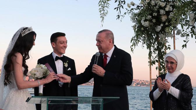 Presiden Turki Recep Tayyip Erdogan (kedua kanan) menyerahkan buku nikah kepada gelandang Arsenal asal Jerman, Mesut Ozil dan Amine Gulse saat menghadiri seremoni pengucapan janji pernikahan mereka di sebuah hotel mewah di Istanbul, Jumat (7/6/2019). (Presidential Press Service via AP, Pool)
