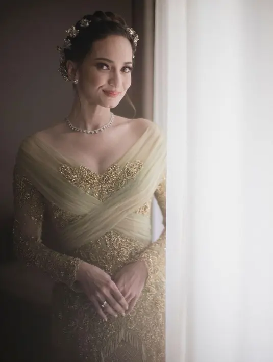 Pada busana kedua, Enzy mengenakan kebaya modifikasi yang memadukan brukat dan aksen tulle yang feminin. Atasan yang elegan ini dipadukan dengan kain songket emas dan heels mules berwarna senada. Enzy pun tidak lagi mengenakan suntiang, melainkan menata rambutnya dengan gaya sanggul modern dengan tusuk konde emas. [Foto: IG/@davidsalimphotography]