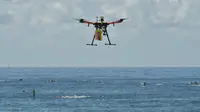 Pesawat tak berawak (drone) pendeteksi hiu berpatroli di atas para peselancar di Pantai Bilgola, utara Sydney, Australia, 10 Desember 2017. Drone ini dilengkapi sistem yang mampu mendeteksi predator bawah air dengan cepat dari udara. (PETER PARKS/AFP)