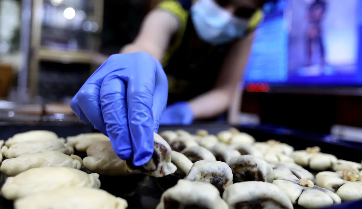 Seorang warga Irak membuat kue tradisional yang dikenal sebagai Kleicha untuk perayaan Idul Fitri di Baghdad, Irak, pada 23 Mei 2020. Kleicha, kue populer yang terbuat dari tepung dan mentega di Irak, dikreasikan dalam berbagai bentuk dengan beragam isian. (Xinhua/Khalil Dawood)