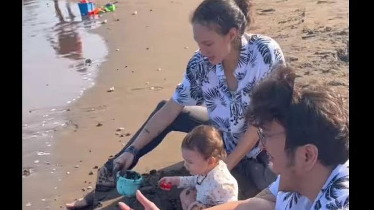 Potret Baby Djiwa tampak main pasir pantai. Tampak Nadine Chandrawinata ikut bermain bersama sang anak.