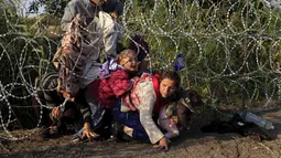 Imigran Suriah merangkak untuk melewati pagar berduri di wilayah Hungaria dekat perbatasan Serbia, wilayah Roszke, Kamis (27/8/2015). Hungaria berencana untuk memperketat perbatasan bagian selatannya dari para pengungsi. (REUTERS/Bernadett Szabo)