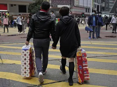 Sepasang suami istri membawa persediaan tisu toilet di sebuah jalan pada Hari Valentine di Hong Kong, Jumat, (14/2/2020). Hari Valentine pada tanggal 14 Februari adalah sebuah hari di mana para kekasih dan mereka yang sedang jatuh cinta menyatakan cintanya. (AP Photo/Kin Cheung)