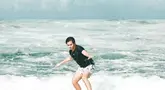Inilah aksi Angga Yunanda saat menjajal berselancar di pantai. Meski pemula, pria 23 tahun ini bisa seimbang berdiri di papan selancar. (Liputan6.com/IG/@angga)