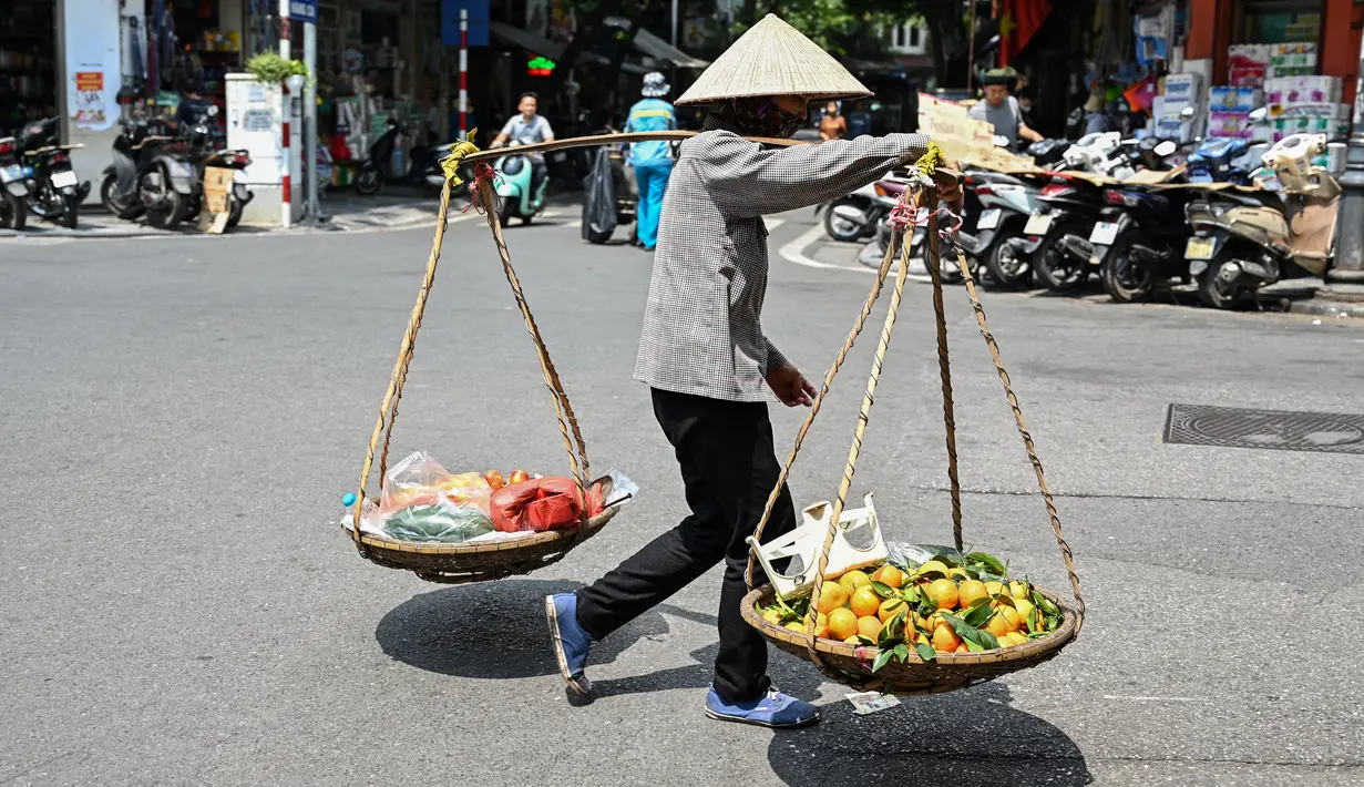 Panas yang menyengat juga berdampak pada para penjual bunga yang menjelajahi gang-gang kecil di Hanoi dengan menggunakan sepeda, dengan ember-ember berisi bunga mawar, aster, dan teratai yang diikatkan di bagian belakang. (Photo by Nhac NGUYEN / AFP)