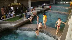Warga mendinginkan diri dalam air di Lapangan Manezhnaya dekat Lapangan Merah, Moskow, Rusia, Jumat (25/6/2021). Warga Moskow kelelahan di bawah suhu panas minggu ini yang mencapai titik tertinggi sepanjang bulan Juni sejak pencatatan mulai disimpan. (AP Photo/Alexander Zemlianichenko)