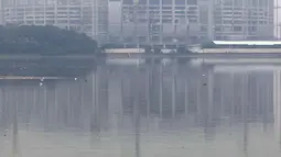 Warga memancing di pinggir Waduk Cincin yang berlatar pembangunan Jakarta International Stadium (JIS), Sabtu (19/6/2021). Pembangunan JIS sudah memasuki tahap pemasangan rangka atap dengan bentang mencapai 269 meter dan ditarget selesai Desember 2021. (Liputan6.com/Helmi Fithriansyah)