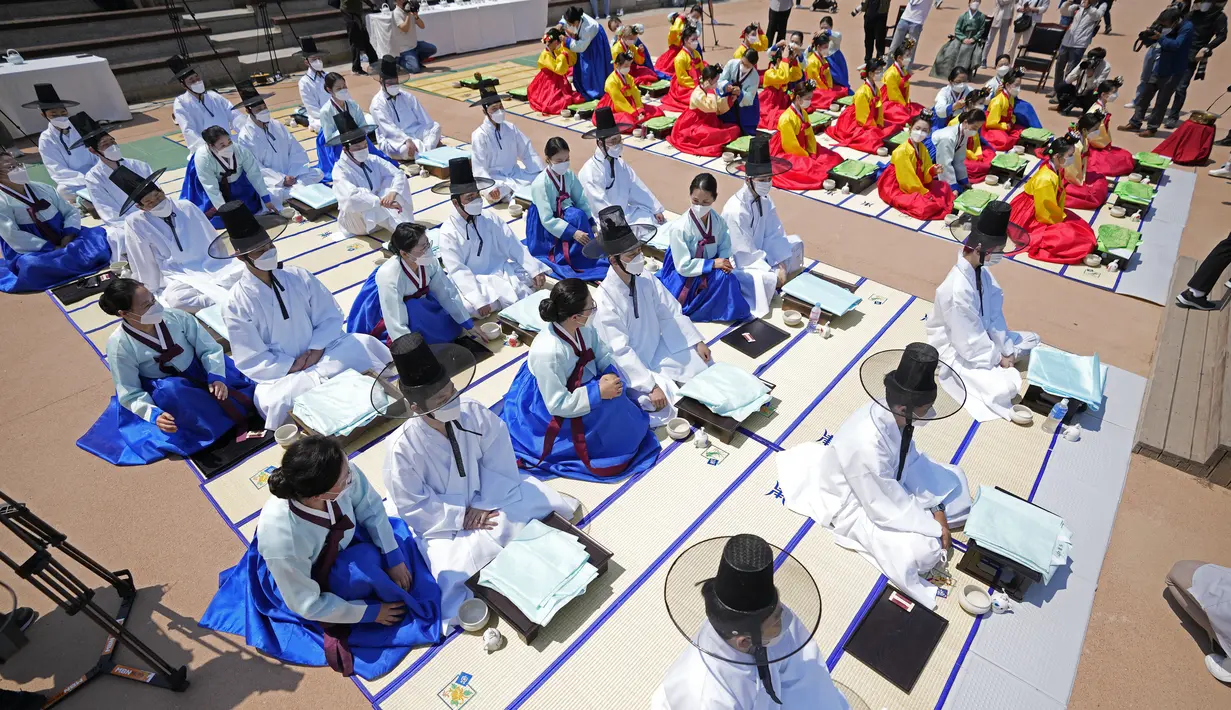 Wanita dan pria mengenakan gaun tradisional Korea Selatan membungkuk selama upacara untuk menghidupkan kembali Hari Kedewasaan ke-50 di Desa Hanok Namsangol di Seoul, Korea Selatan (16/5/2022). Upacara diadakan untuk pria dan wanita muda yang akan berusia 20 tahun. (AP Photo/Lee Jin-man)