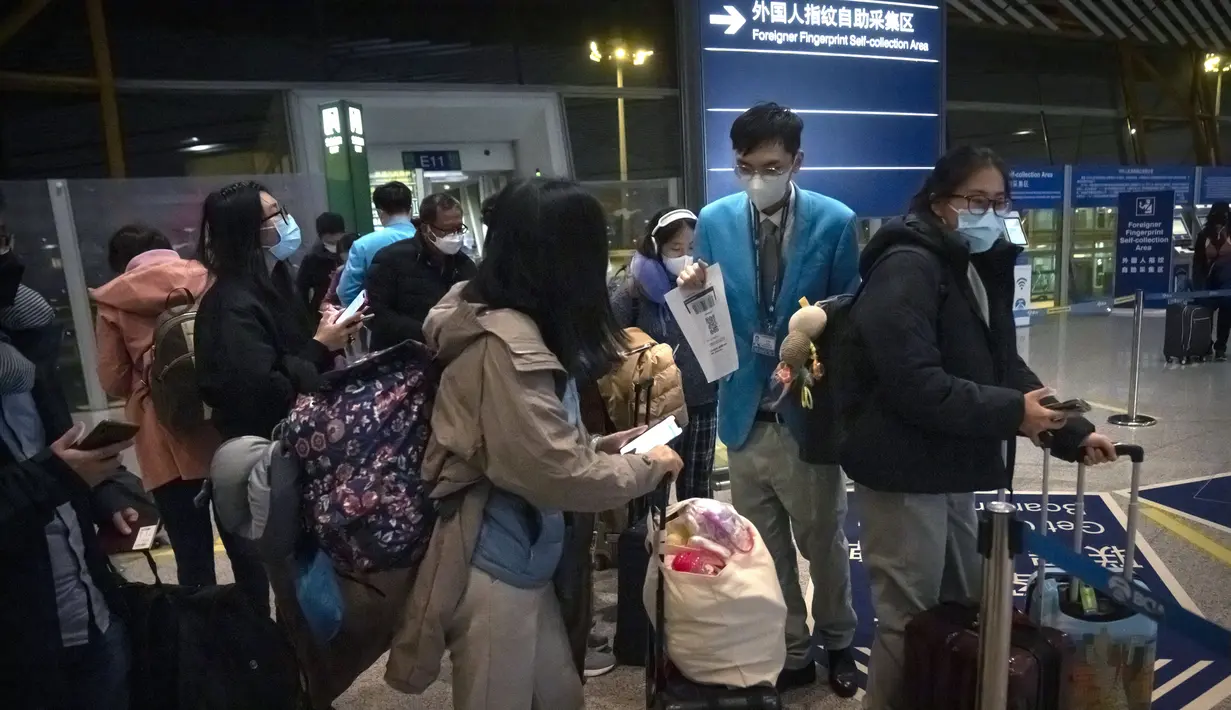Pekerja membantu pelancong mengisi status kesehatan elektronik COVID-19 mereka di area kedatangan internasional di Bandara Internasional Beijing, China (9/1/2023). Pelancong internasional pertama tiba di China tanpa karantina wajib yang telah diberlakukan pada awal penerbangan. Pandemi tiga tahun lalu setelah pembatasan dicabut mulai hari Minggu. (AP/Mark Schiefelbein)