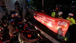 Petugas kepolisian Satlantas Jakarta Pusat membentangkan spanduk sosialisasi larangan berhenti pada garis stop di kawasan Cideng, Jakarta, Senin (23/2). (Liputan6.com/Johan Tallo)