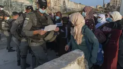 Wanita Palestina menunggu untuk menyeberangi pos pemeriksaan Qalandia antara kota Ramallah Tepi Barat dan Yerusalem, untuk menghadiri sholat Jumat pertama di masjid al-Aqsa, selama bulan suci Ramadhan, Jumat (16/4/2021).  (AP Photo/Nasser Nasser)