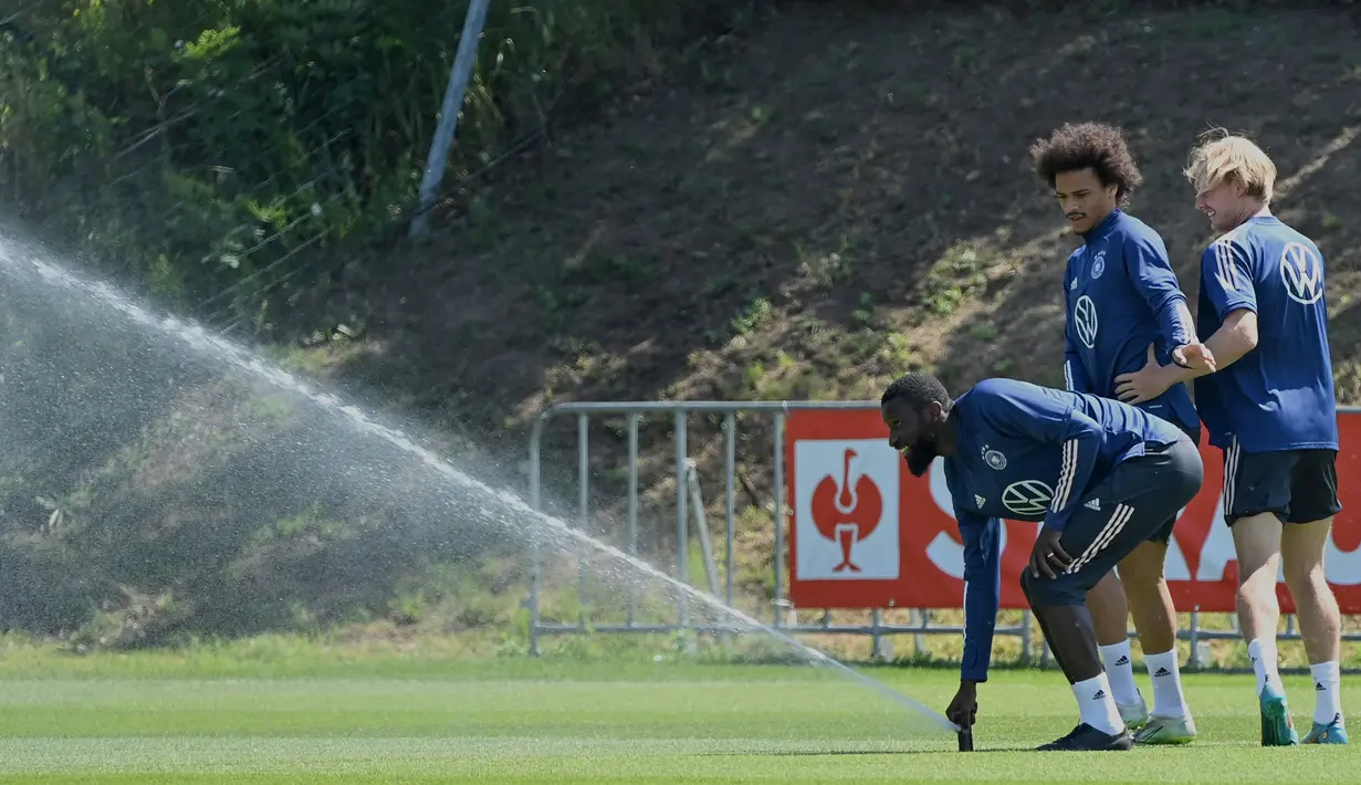 (kiri-kanan) Pemain Jerman Antonio Ruediger, Leroy Sane, dan Julian Brandt bermain dengan sprinkler saat sesi latihan di pusat olahraga BVSC, Budapest, Hungaria, 13 Juni 2022. Jerman akan menghadapi Italia pada pertandingan sepak bola UEFA Nations League. (Attila KISBENEDEK/AFP)